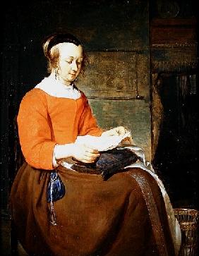 A young woman seated in an interior, reading a letter