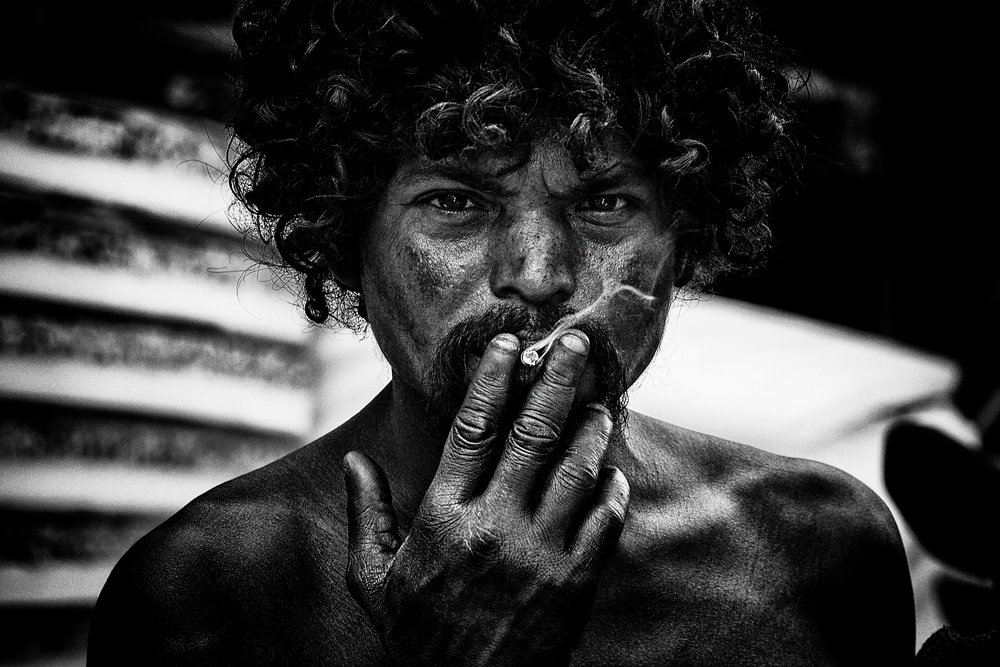 A homeless man smoking in the streets of Delhi. de Joxe Inazio Kuesta Garmendia