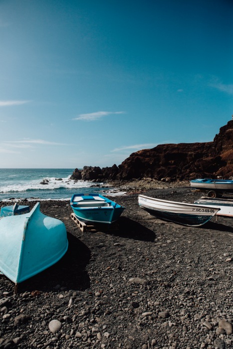 Blaue Boote auf schwarzem Vulkansstrand auf Lanzarote de Laura Nenz