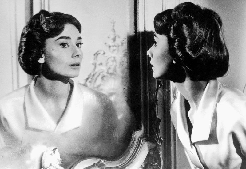 Actress Audrey Hepburn looking at her reflection in the mirror de 