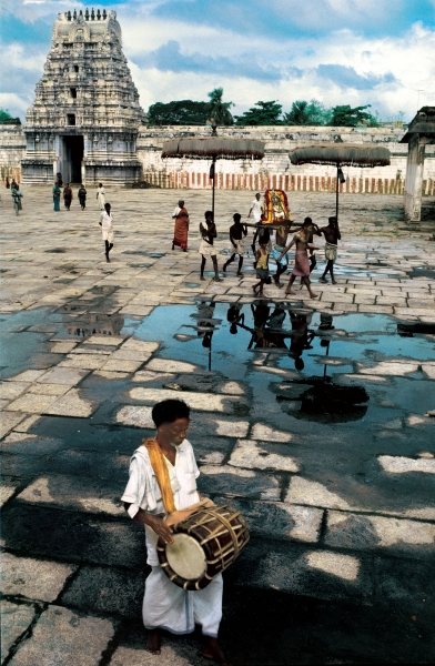 Drummer and devotees reflected in pool of water (photo)  de 