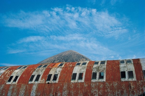 Rusted roof of a deserted warehouse with the breast of a mountain (photo)  de 