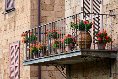 Romantischer Balkon mit roten Blumen in Tonkruegen