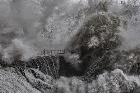 A huge sea wave crashes on the military dock